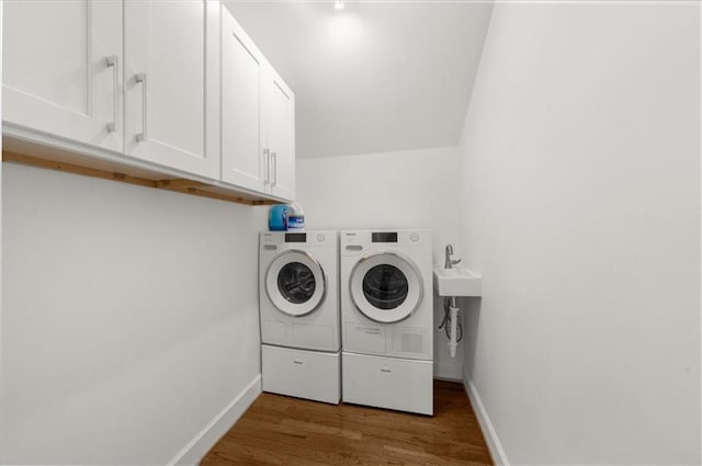 laundry area with cabinet space, separate washer and dryer, dark wood-type flooring, and baseboards
