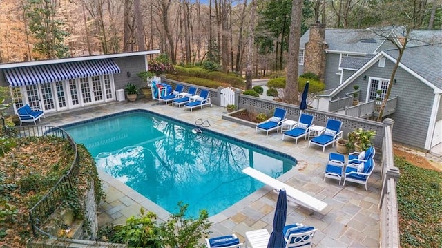 view of swimming pool featuring a diving board, french doors, a patio, and fence