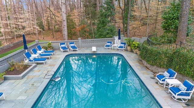 view of pool featuring a fenced in pool, fence, a patio area, and a diving board