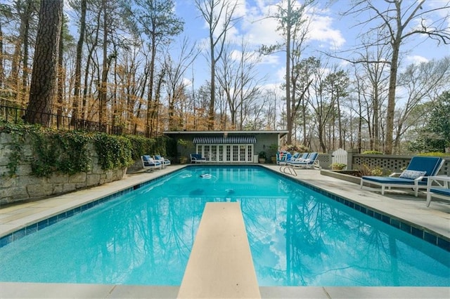 view of swimming pool featuring a diving board, a fenced in pool, fence, and a patio area
