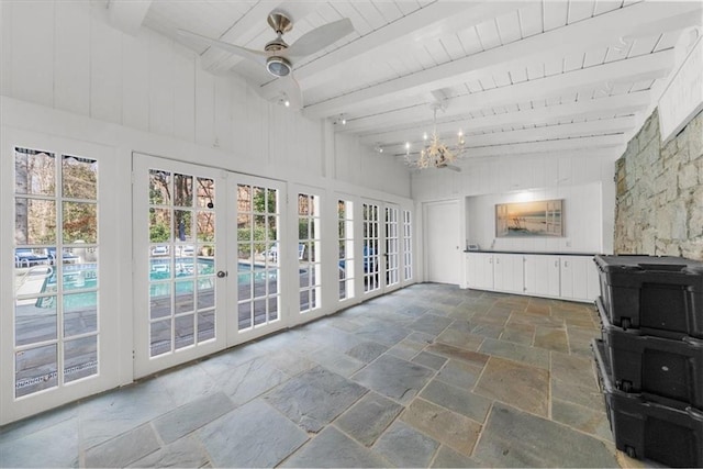 unfurnished sunroom with ceiling fan with notable chandelier, french doors, and vaulted ceiling with beams