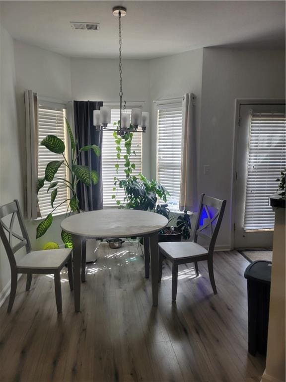 dining space with visible vents, an inviting chandelier, and wood finished floors