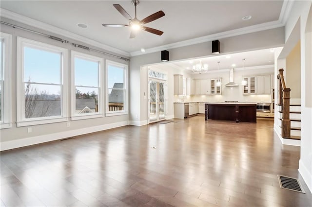 unfurnished living room featuring ceiling fan with notable chandelier, crown molding, and dark wood-type flooring