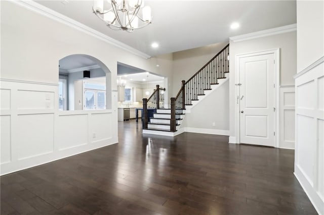 foyer with ornamental molding, dark wood-type flooring, and a chandelier