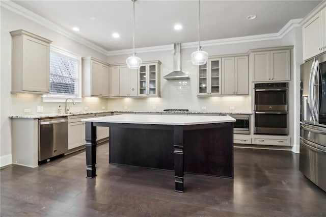 kitchen with wall chimney exhaust hood, dark hardwood / wood-style floors, pendant lighting, a kitchen island, and appliances with stainless steel finishes