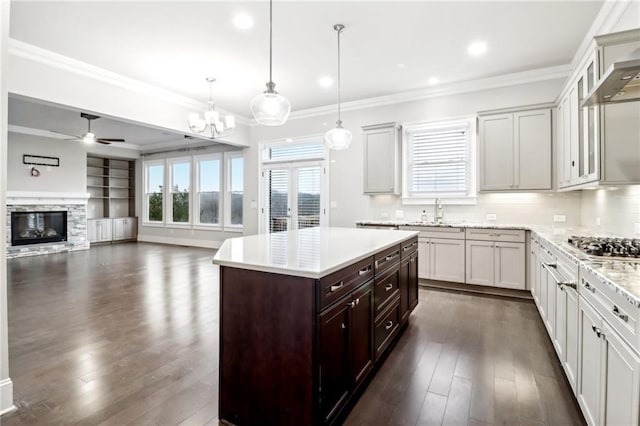 kitchen featuring dark hardwood / wood-style flooring, dark brown cabinetry, a fireplace, a kitchen island, and hanging light fixtures