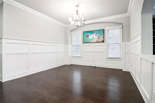 unfurnished dining area with dark hardwood / wood-style floors, crown molding, and a chandelier