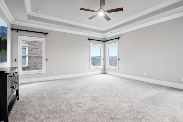 empty room with ceiling fan, a raised ceiling, carpet floors, and crown molding