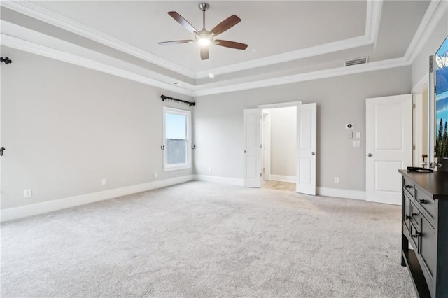 unfurnished bedroom with a tray ceiling, ceiling fan, crown molding, and light colored carpet