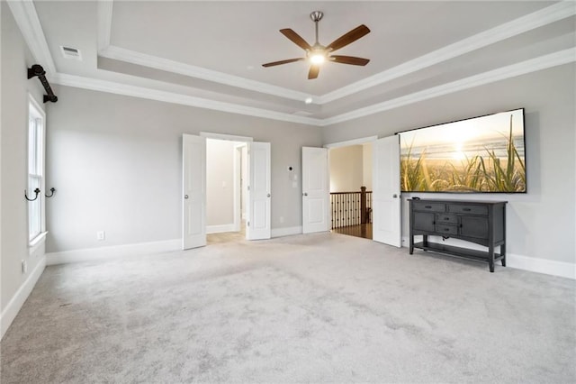 unfurnished bedroom with ceiling fan, a raised ceiling, carpet floors, and crown molding