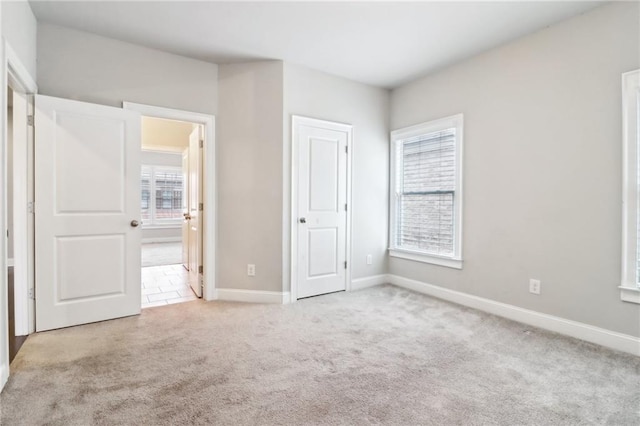 unfurnished bedroom featuring light carpet and multiple windows