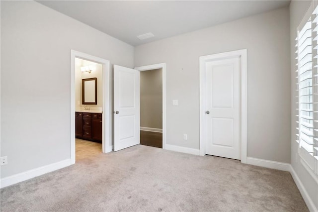 unfurnished bedroom featuring ensuite bathroom, light colored carpet, and sink