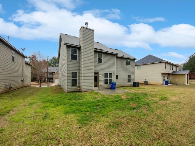 rear view of property with a lawn, a patio, a chimney, and central AC