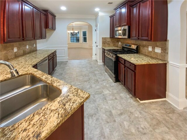 kitchen featuring arched walkways, reddish brown cabinets, and stainless steel appliances