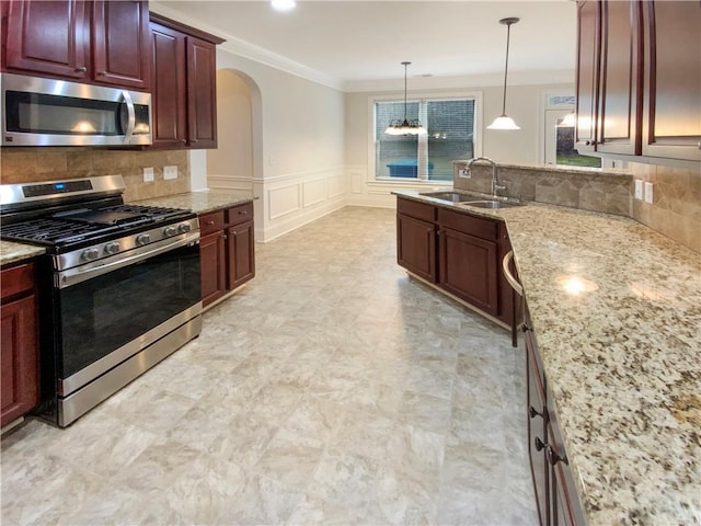 kitchen with ornamental molding, a sink, tasteful backsplash, arched walkways, and appliances with stainless steel finishes