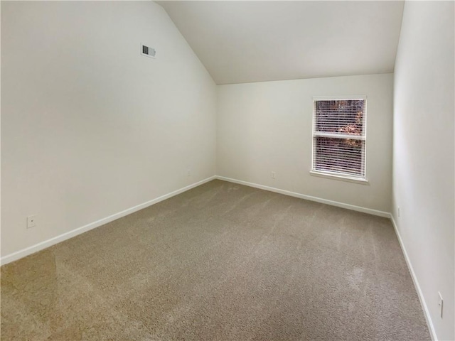 empty room with vaulted ceiling, carpet, visible vents, and baseboards