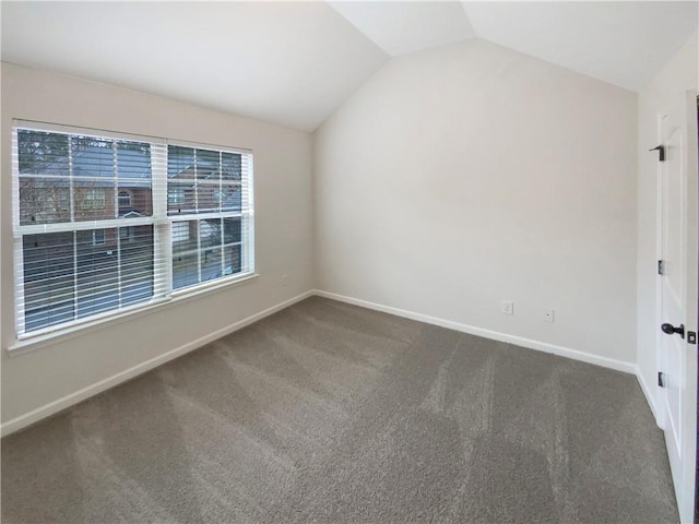 carpeted empty room featuring vaulted ceiling and baseboards