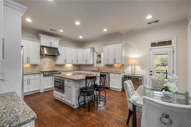 kitchen featuring under cabinet range hood, visible vents, appliances with stainless steel finishes, and dark wood-type flooring