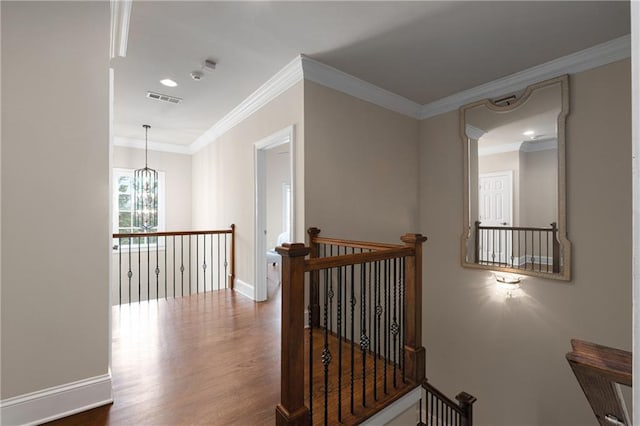 corridor featuring wood finished floors, an upstairs landing, visible vents, and ornamental molding