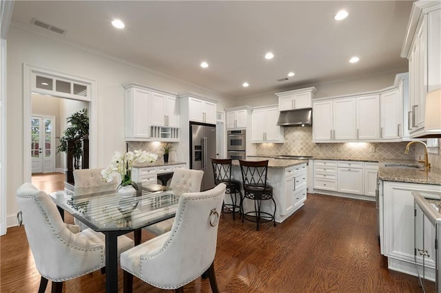 dining area with dark wood finished floors, crown molding, and visible vents