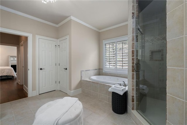 bathroom featuring baseboards, ornamental molding, a shower stall, a garden tub, and tile patterned floors