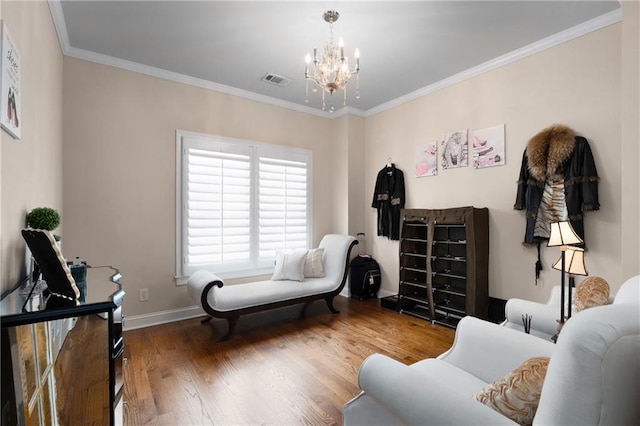 sitting room featuring visible vents, wood finished floors, an inviting chandelier, crown molding, and baseboards