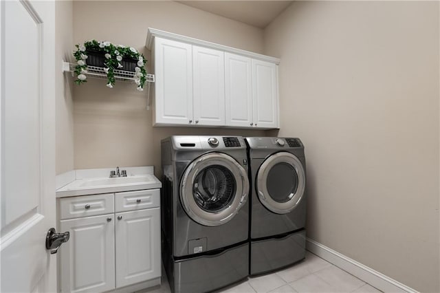 laundry room featuring independent washer and dryer, a sink, cabinet space, light tile patterned flooring, and baseboards