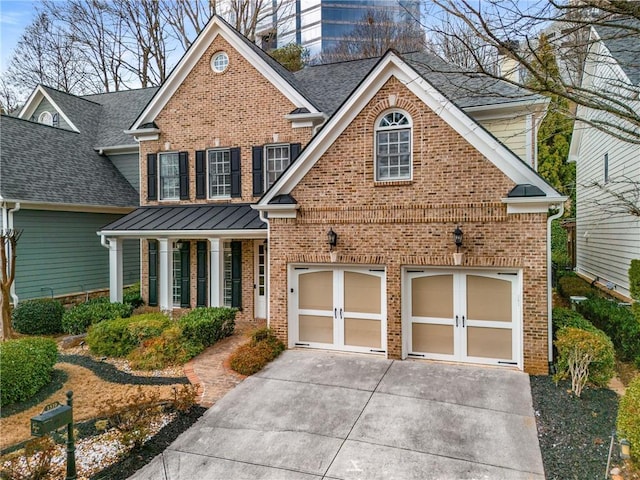 traditional-style home with a standing seam roof, metal roof, concrete driveway, a garage, and brick siding