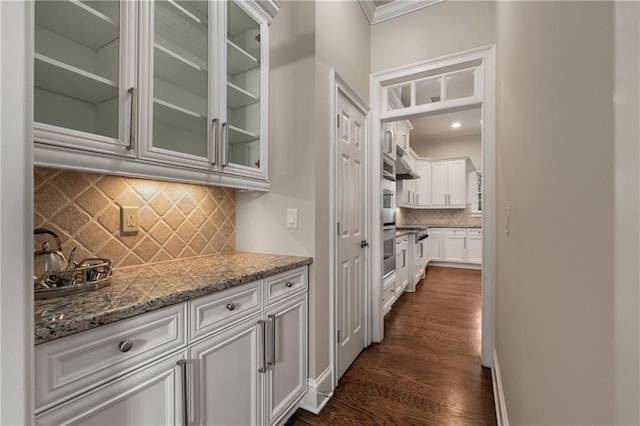 interior space featuring dark wood-style floors, baseboards, ornamental molding, decorative backsplash, and exhaust hood