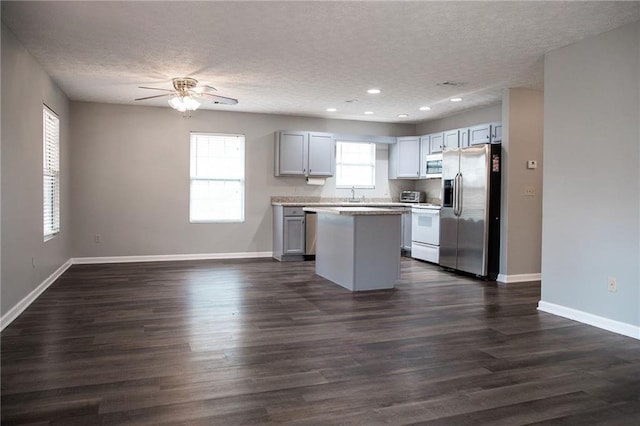 kitchen featuring a center island, stainless steel appliances, dark wood-type flooring, and baseboards