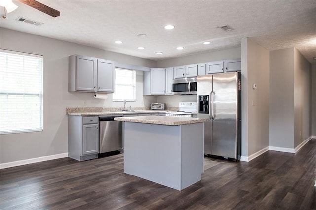 kitchen featuring a center island, visible vents, dark wood-style flooring, and stainless steel appliances