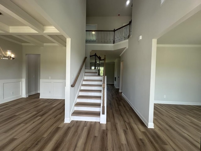 3799 Cheyenne Ln, Jefferson, GA 30549 - stairs featuring a chandelier, wood finished floors, wainscoting, beam ceiling, and a high ceiling