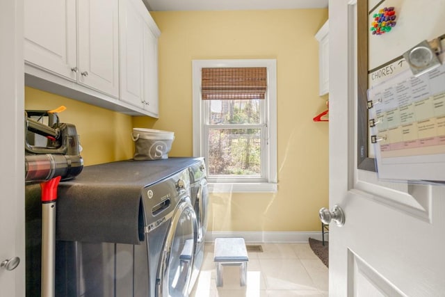 laundry area with light tile patterned floors, separate washer and dryer, visible vents, baseboards, and cabinet space
