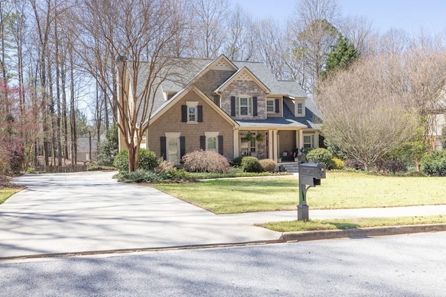 view of front of house with a front lawn, stone siding, and concrete driveway