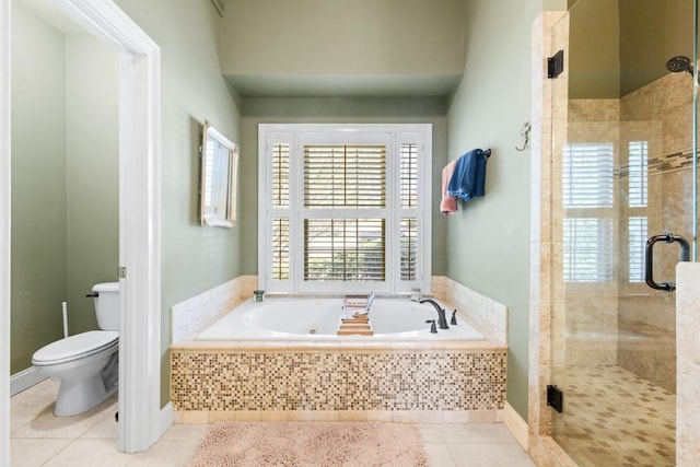 bathroom featuring toilet, tile patterned floors, a shower stall, and a garden tub