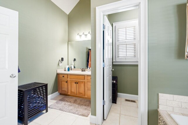 full bath featuring visible vents, baseboards, tiled bath, vanity, and tile patterned floors