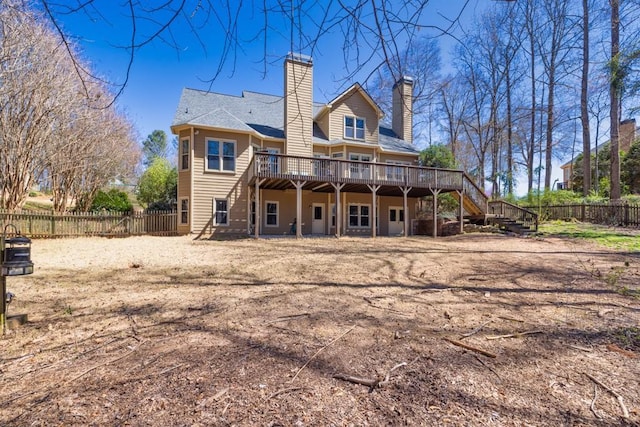rear view of property with a deck, a chimney, fence, and stairway