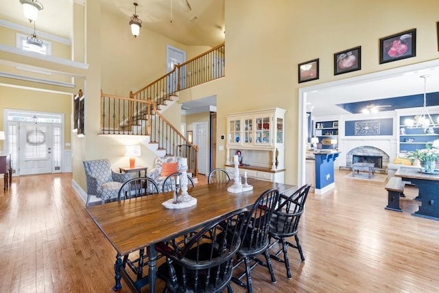 dining room with a fireplace, stairway, a towering ceiling, and wood finished floors