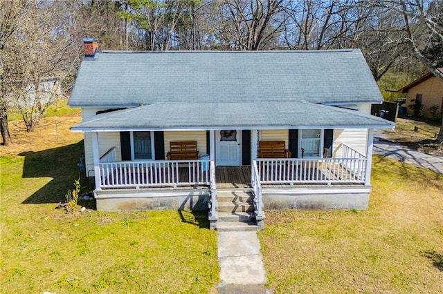 view of front of property with a chimney, a porch, and a front lawn