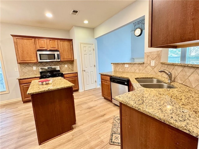 kitchen featuring light stone counters, visible vents, light wood-style flooring, a sink, and stainless steel appliances