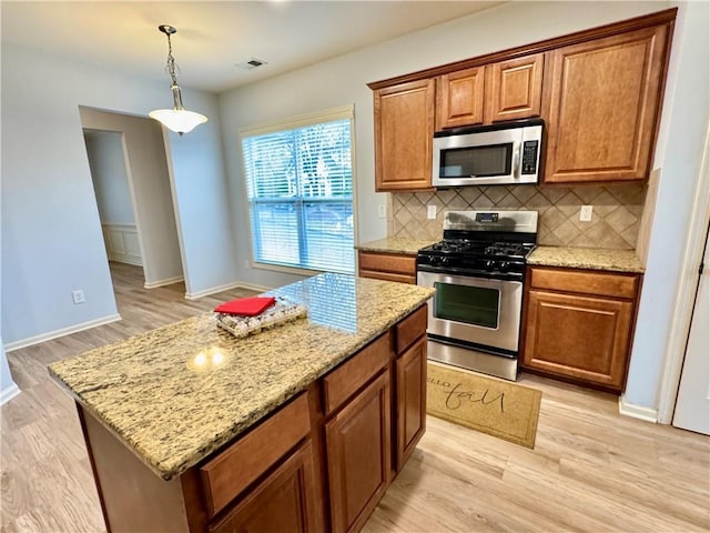 kitchen with visible vents, light stone counters, light wood-style flooring, appliances with stainless steel finishes, and brown cabinets