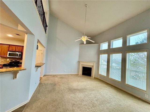 unfurnished living room with light carpet, a fireplace with flush hearth, a high ceiling, and baseboards