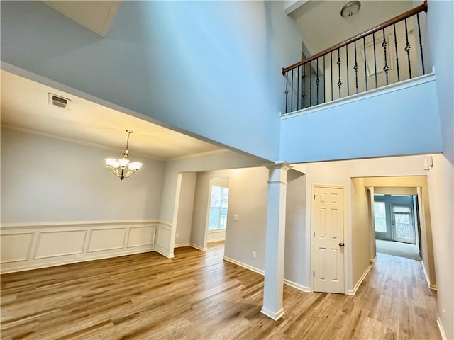 interior space with visible vents, plenty of natural light, light wood-style flooring, and decorative columns