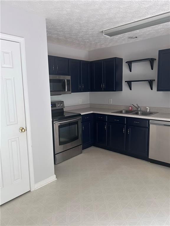 5425 Village Green Sq, Norcross, GA 30093 - kitchen featuring appliances with stainless steel finishes, a sink, light floors, light countertops, and a textured ceiling