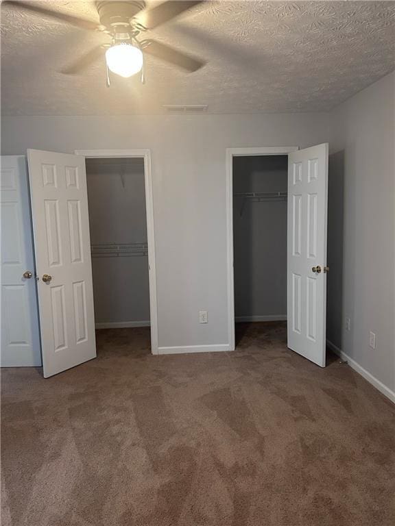 5425 Village Green Sq, Norcross, GA 30093 - unfurnished bedroom featuring multiple closets, carpet, a textured ceiling, baseboards, and a ceiling fan