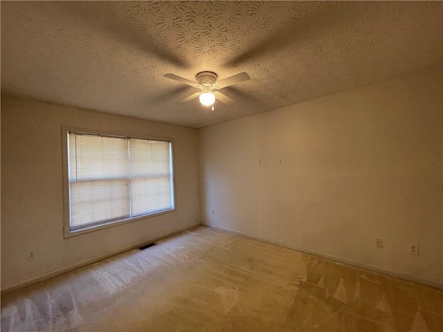 spare room featuring a textured ceiling, light colored carpet, and ceiling fan