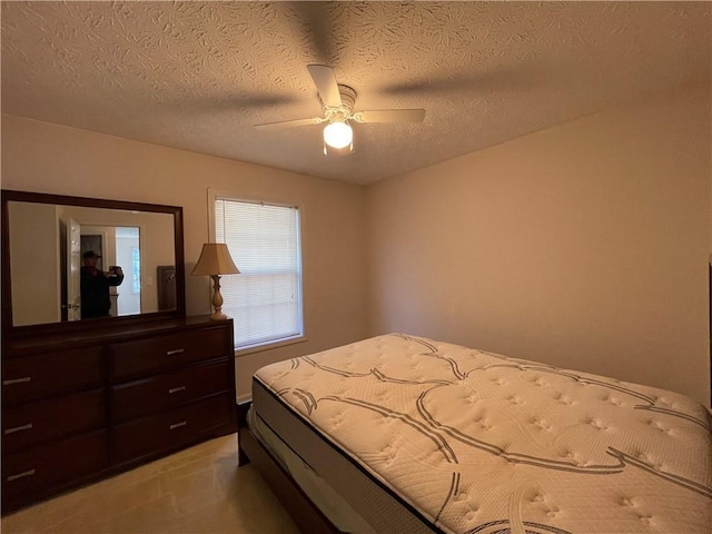 carpeted bedroom featuring ceiling fan and a textured ceiling