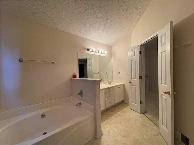 bathroom featuring a bathing tub, vanity, and a textured ceiling