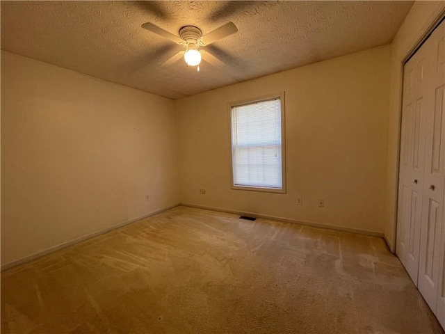 unfurnished bedroom with light carpet, a textured ceiling, a closet, and ceiling fan