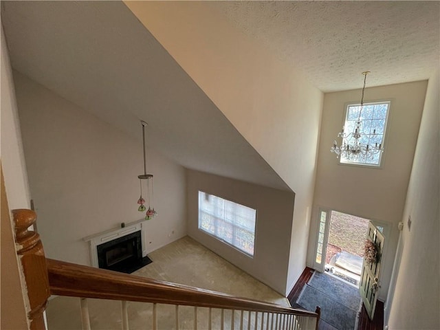 staircase with a notable chandelier, carpet floors, a textured ceiling, and a towering ceiling